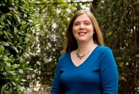 a woman smiling in front of a bush